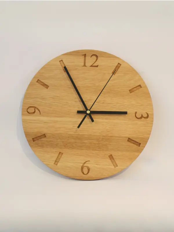 Handmade oak clock engraved with numbers 12, 3, 6, and 9, with line markers for other hours. Shown with black clock hands.
